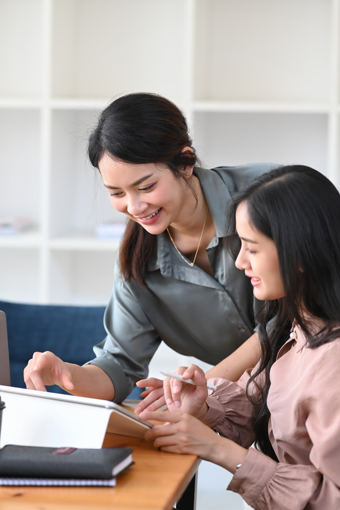 Smiling,Young,Female,Employee,Helping,Her,Colleague,Working,In,Office. Employee Shared Plan in Malaysia